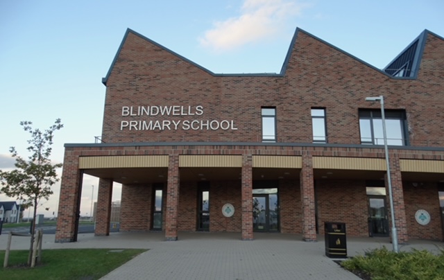 The front of Blindwells Primary School, a red-brick building with the school name on the wall