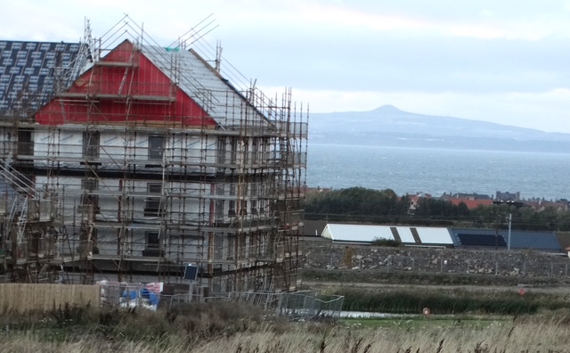 Homes under scaffolding with the Firth of Forth beyond