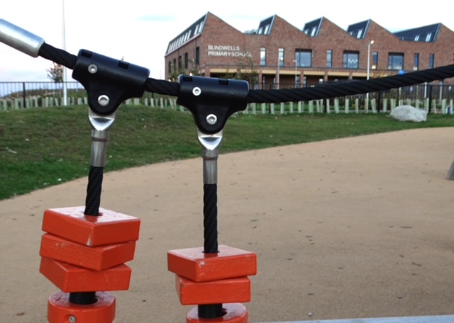 Rope climbing frame in the playground, with Blindwells Primary School behind