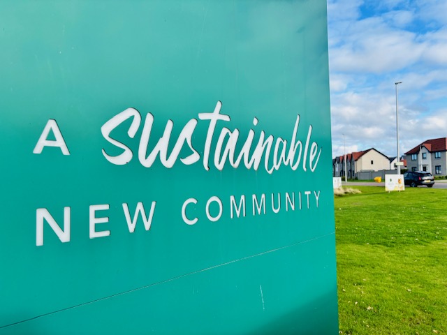 Green sign reading A Sustainable New Community